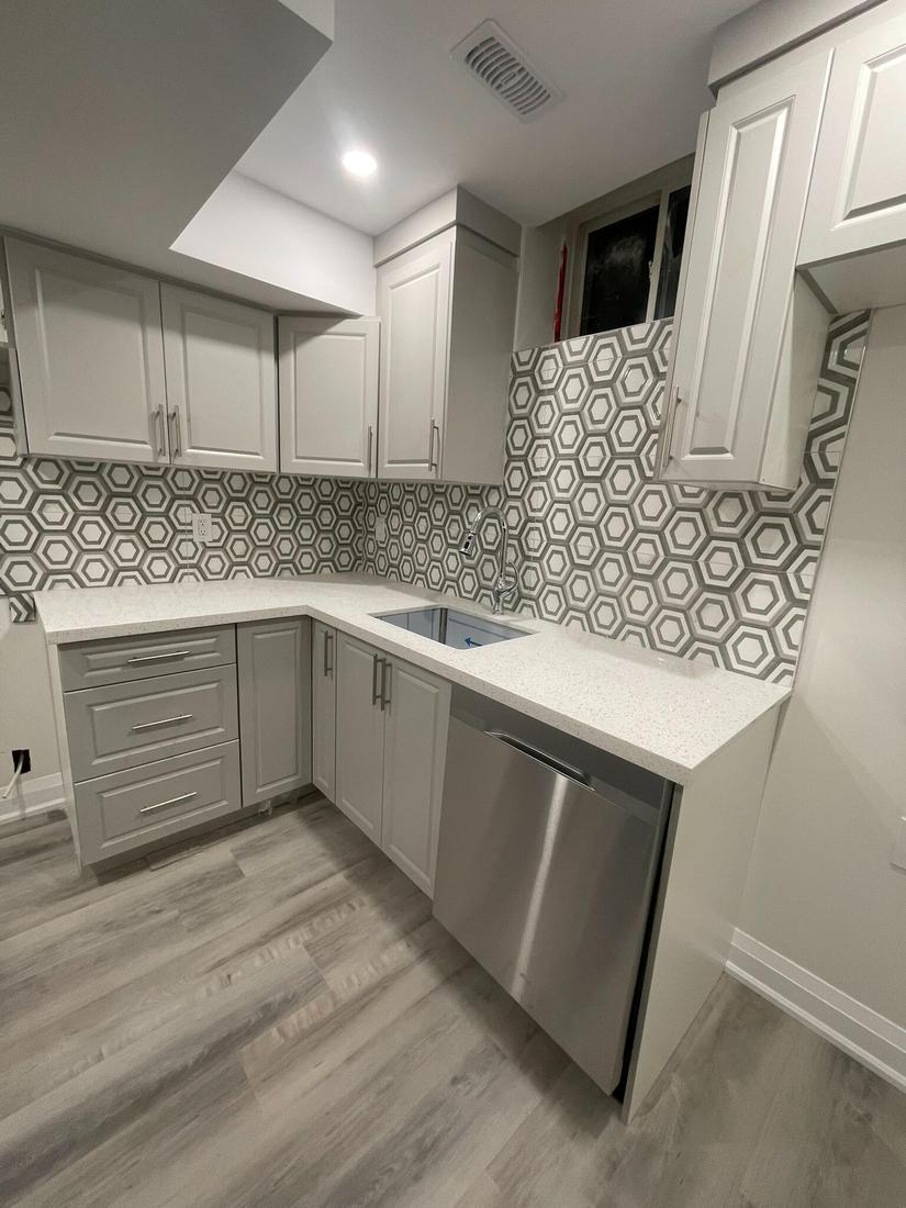 Basement kitchen upgrade with modern cabinetry, geometric tile backsplash, and quartz counters.
