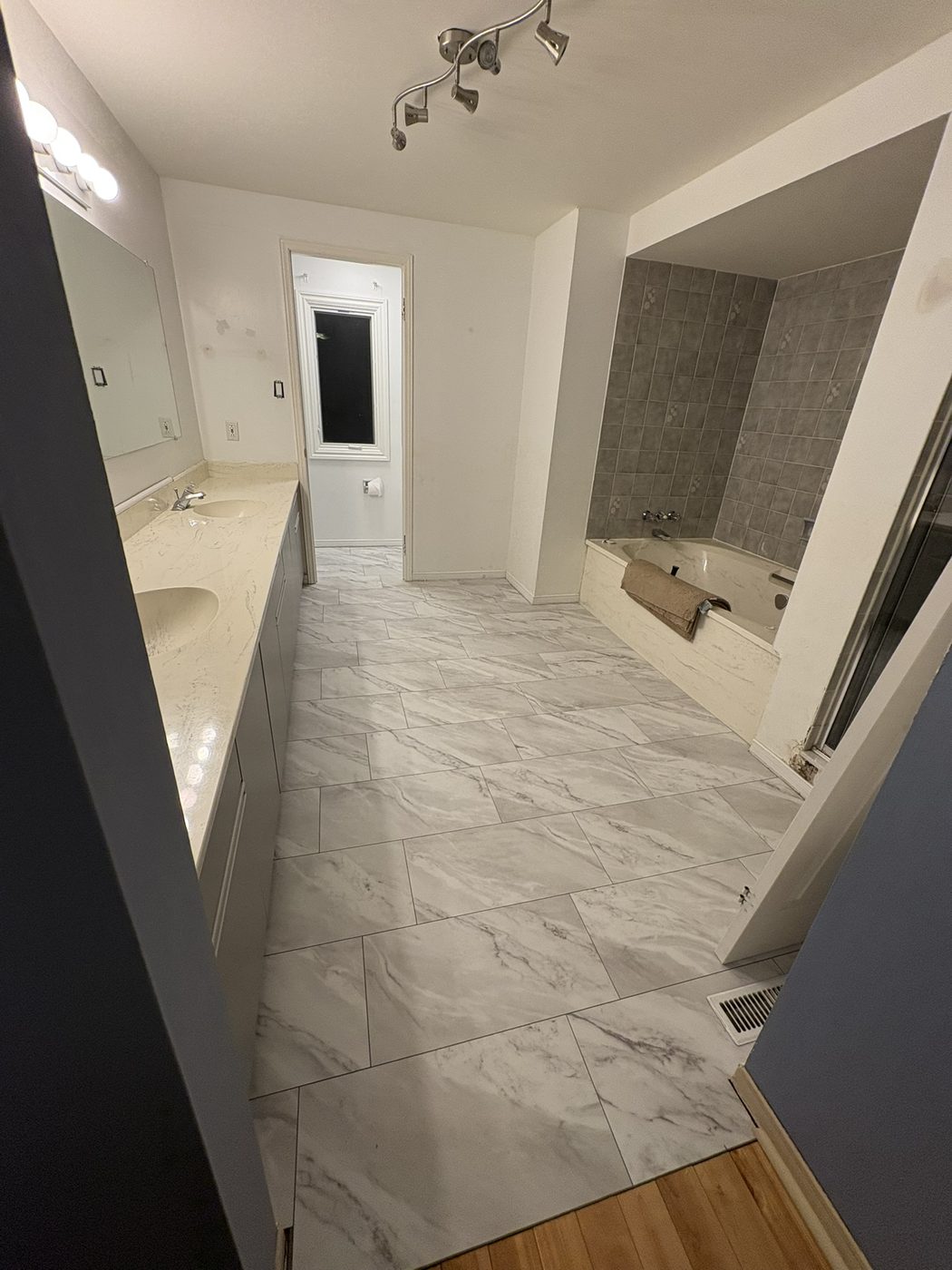 Ensuite retreat with soaker tub, double vanity, and large-format tile flooring.