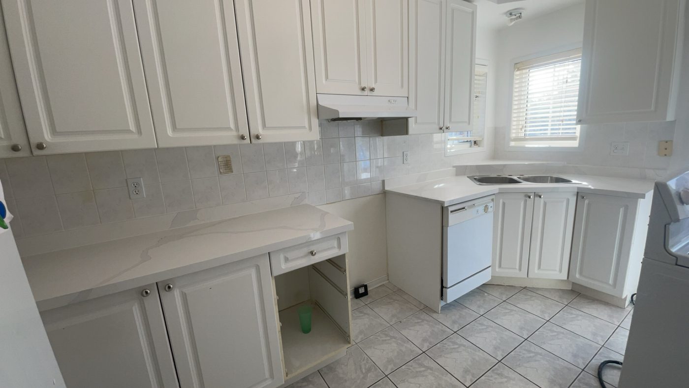 Two-tone kitchen with granite counters, tile backsplash, and an open dining nook.